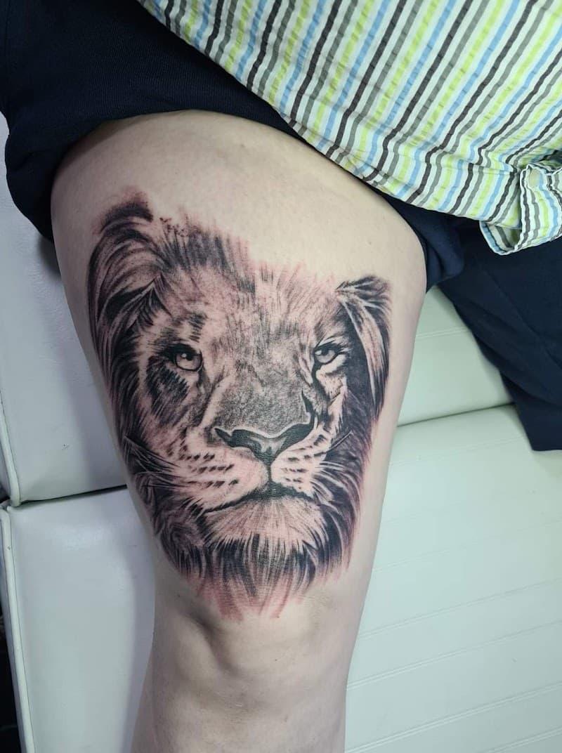 Realistische leeuwenkop tattoo op het bovenbeen.
