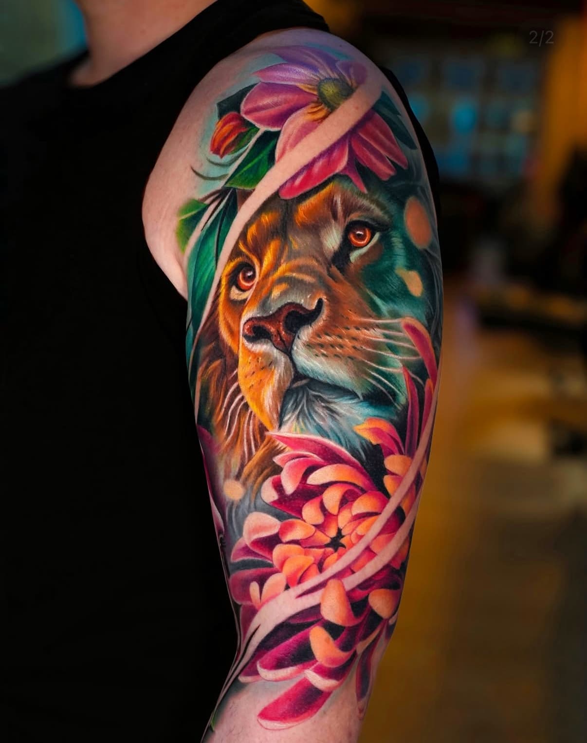 Kleurrijke realistische leeuw met bloemen op bovenarm.