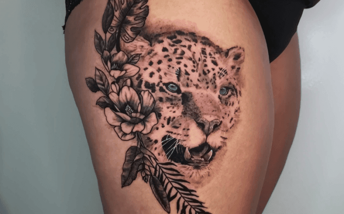 Realistische luipaard met blauwe ogen en bloemen op bovenbeen.