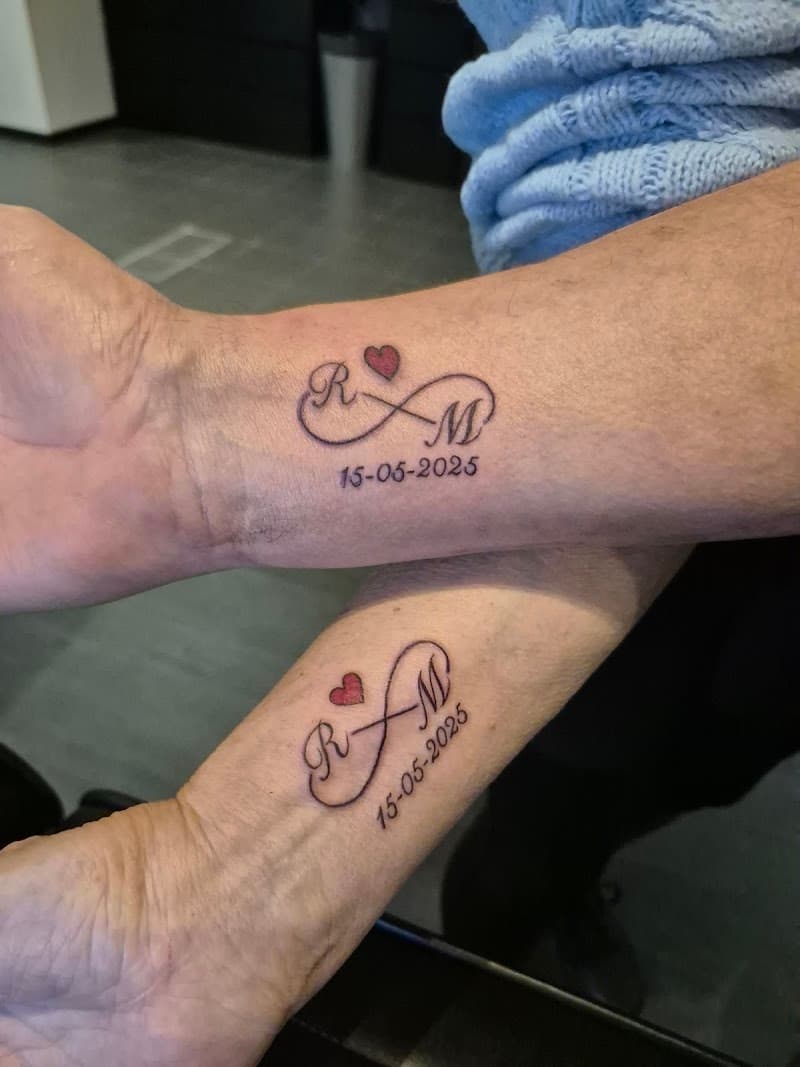 Twee polsen met identieke infinity tattoos, initialen R&M, hartje en datum.
