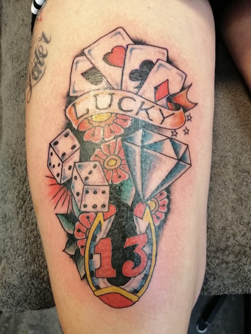 Traditional tattoo met kaarten, dobbelstenen, hoefijzer en 'Lucky 13'.