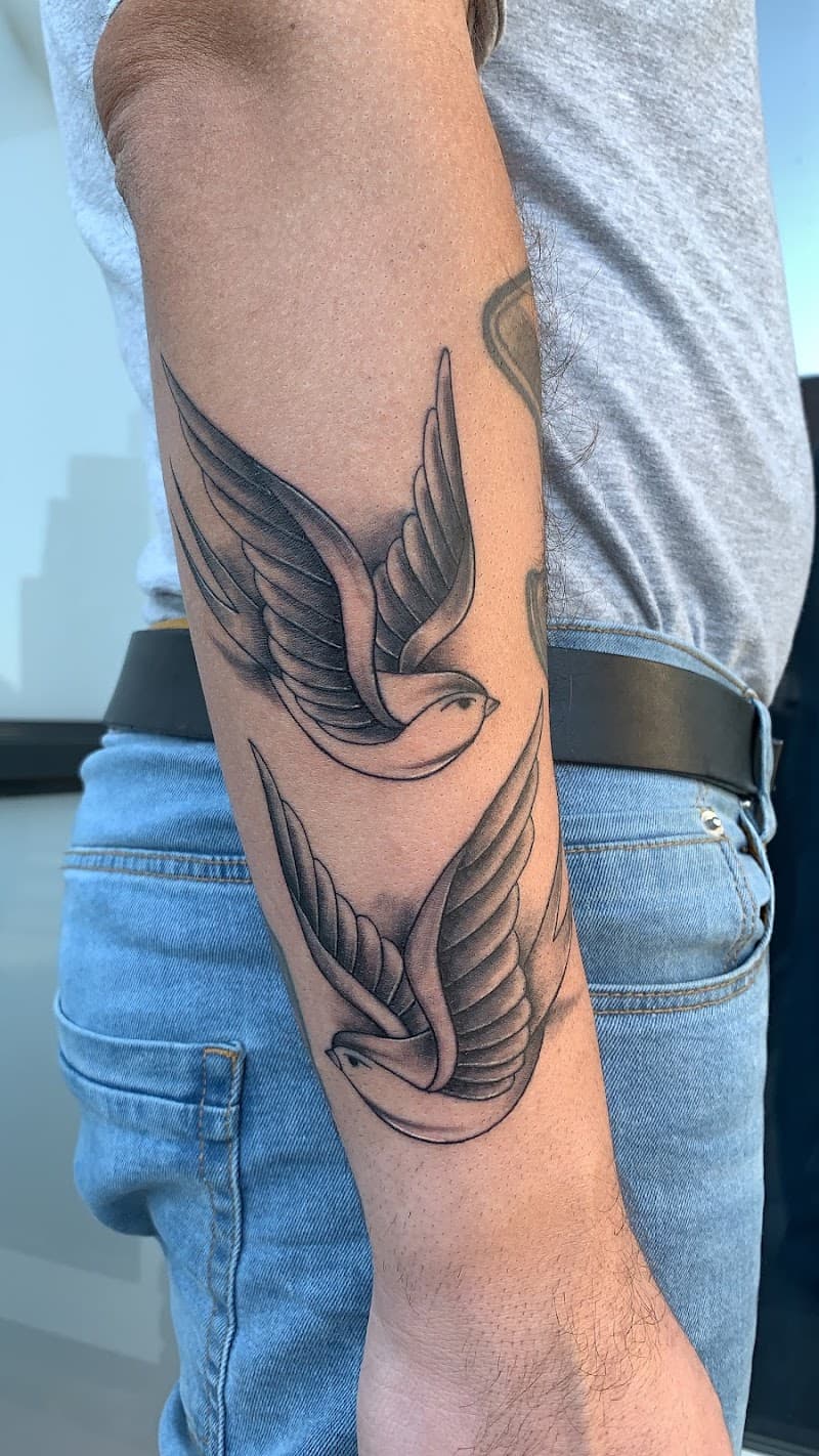 Twee traditionele zwaluwen in zwart-wit op de onderarm.