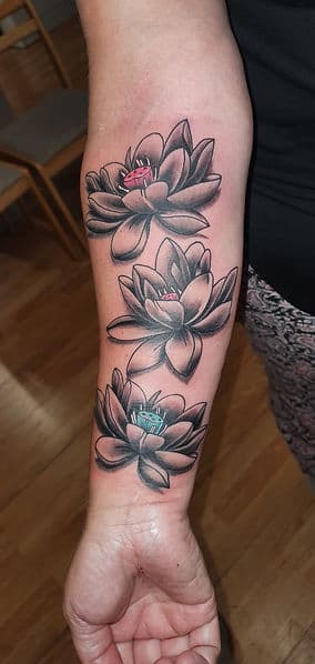 Drie lotusbloemen in zwart-wit met gekleurde harten op de onderarm.