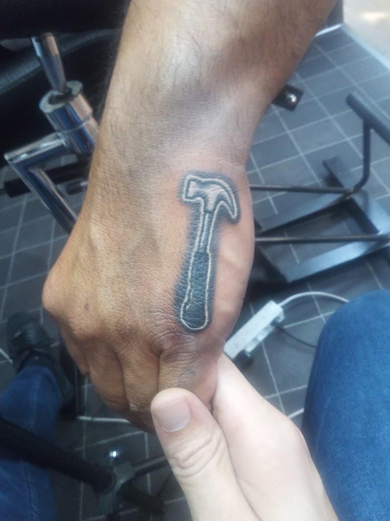 Kleine, minimalistische hamer tattoo op de hand.