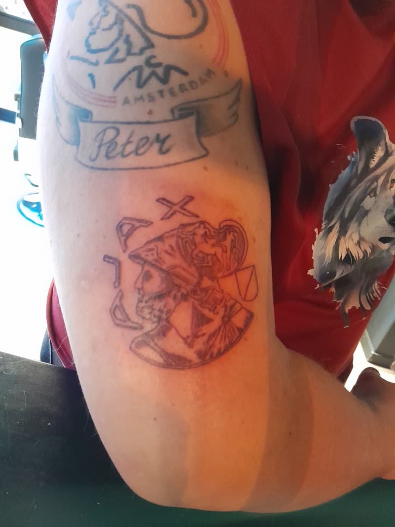 Twee Ajax Amsterdam tattoos op bovenarm, één oud en één vers.