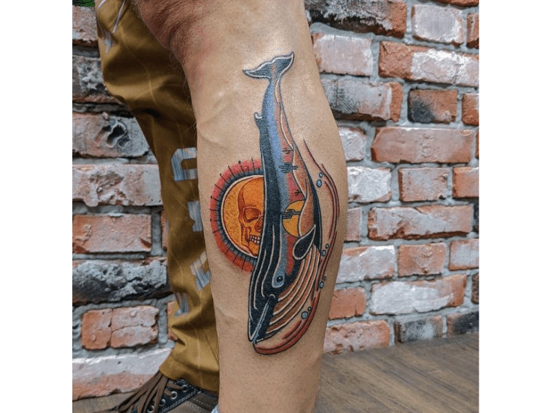 Traditionele tattoo van een walvis met een woestijnlandschap en schedel erin.