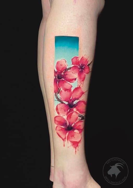 Aquarel kersenbloesem tattoo in een rechthoekig kader op het onderbeen.