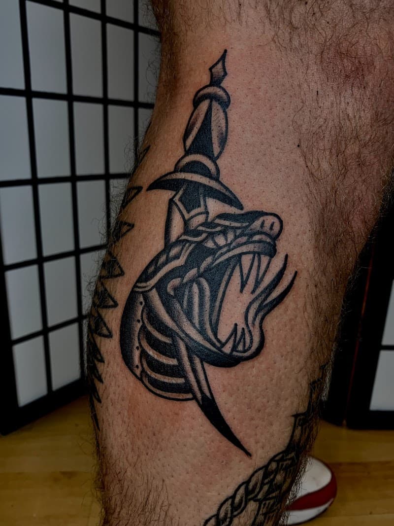 Zwart-wit traditionele tattoo van een panterkop doorboord met een dolk.