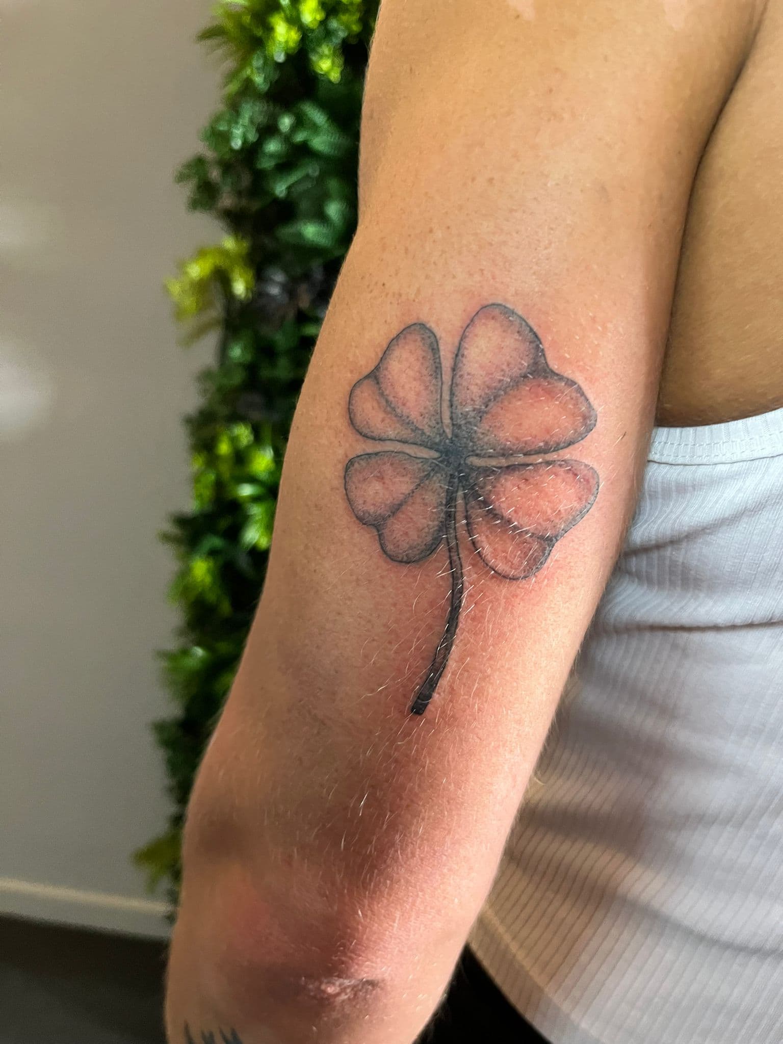 Eenvoudige blackwork klavertje vier tattoo op de bovenarm.