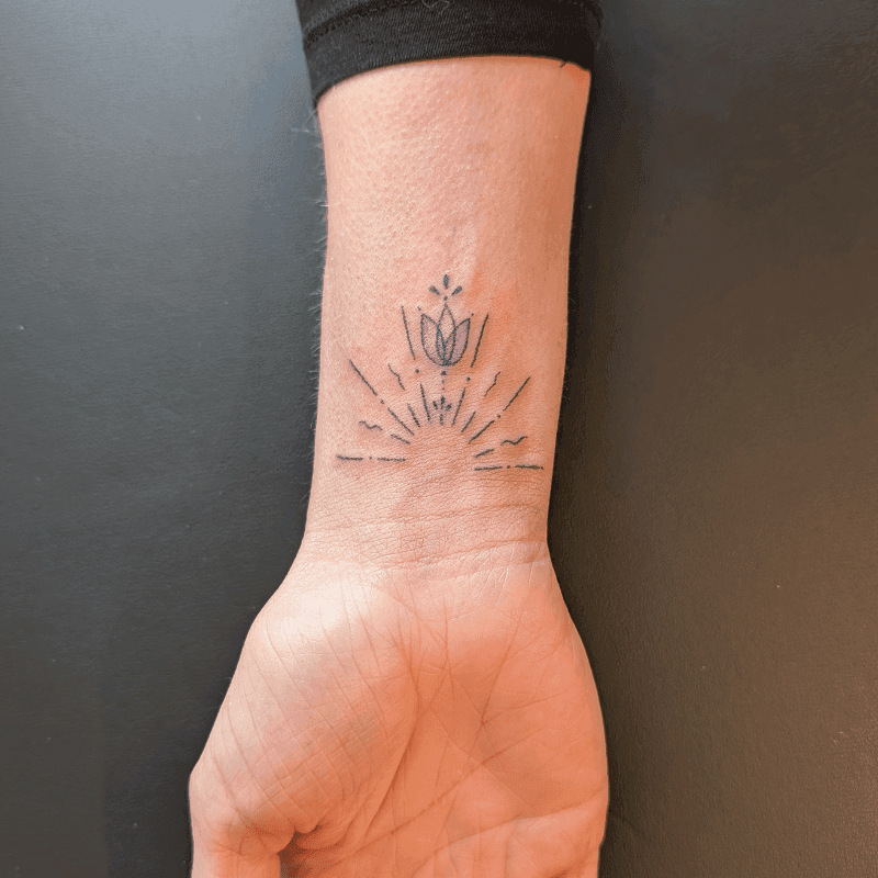 Minimalistische lotus met zonnestralen op de pols.