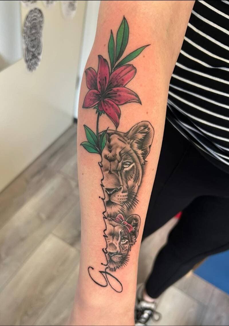 Leeuwin en welp met roze lelie en naam 'Gianni' op onderarm.