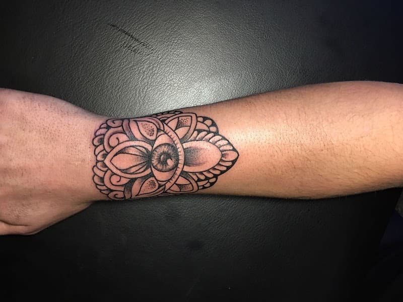 Zwart-wit mandala tattoo met een oog in het midden op de pols.