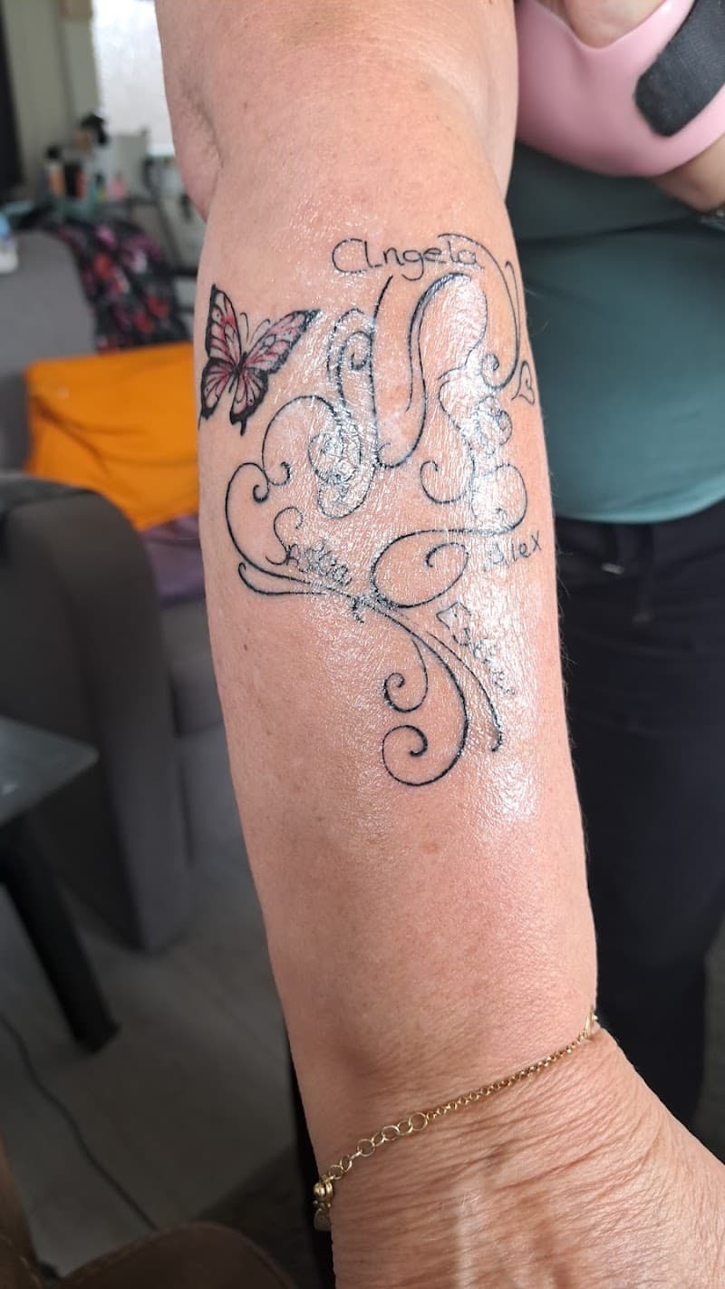 Sierlijke lettertattoo met namen en vlinder op onderarm.