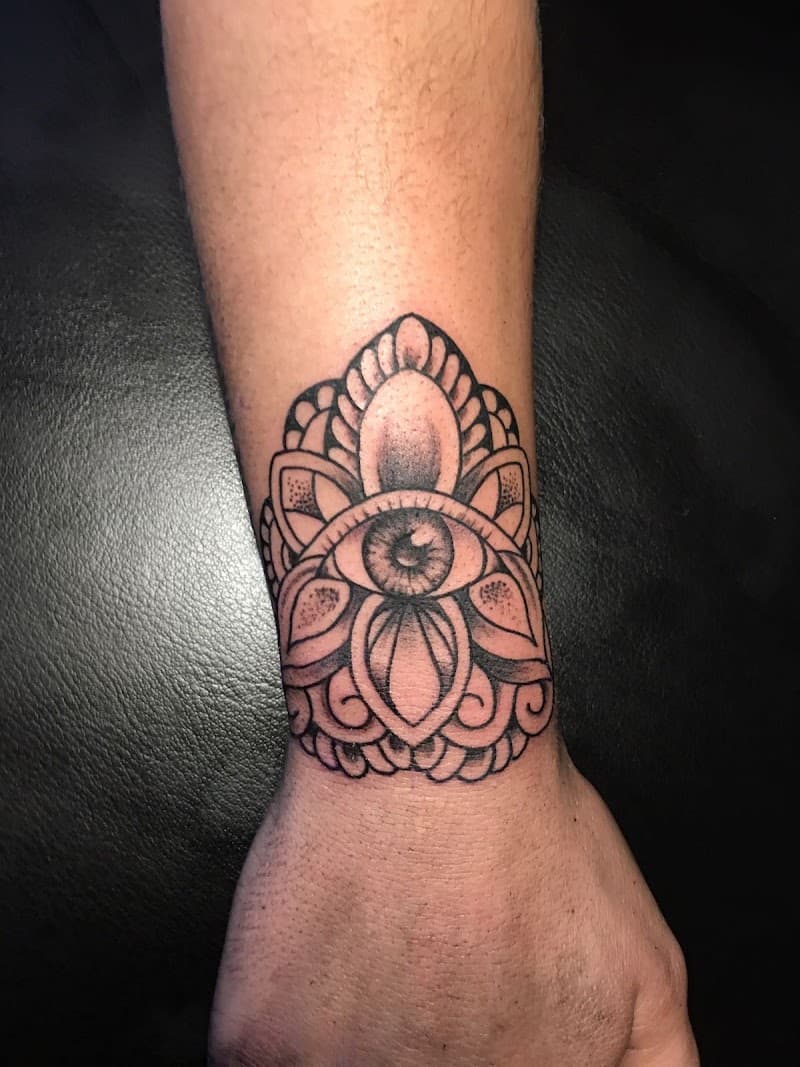 Mandala tattoo met een oog in het midden op de pols.