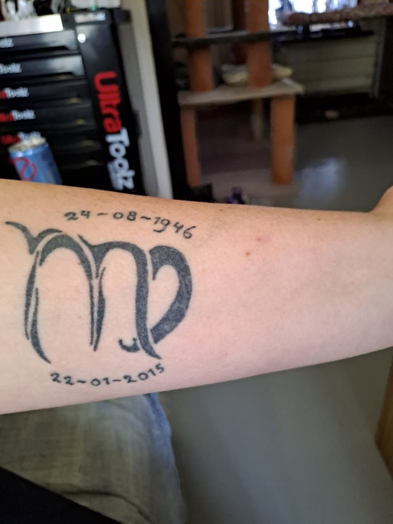 Zwart-wit Maagd sterrenbeeld symbool met twee datums op de onderarm.