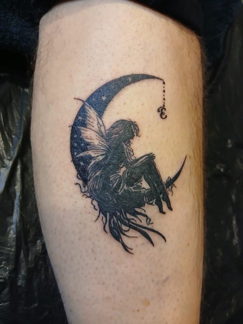 Zwart-wit tattoo van een fee zittend op een halve maan.
