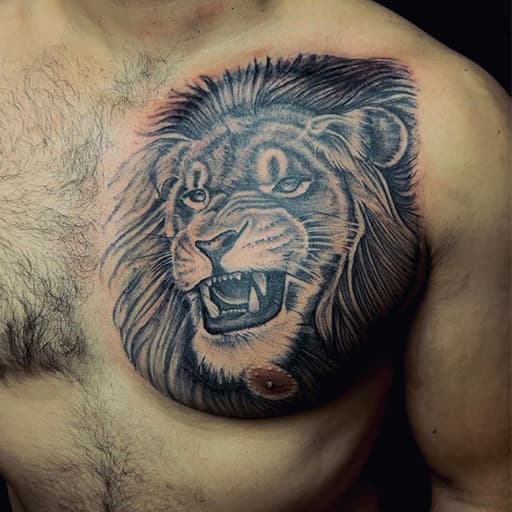 Realistische leeuwenkop tattoo op de borst.