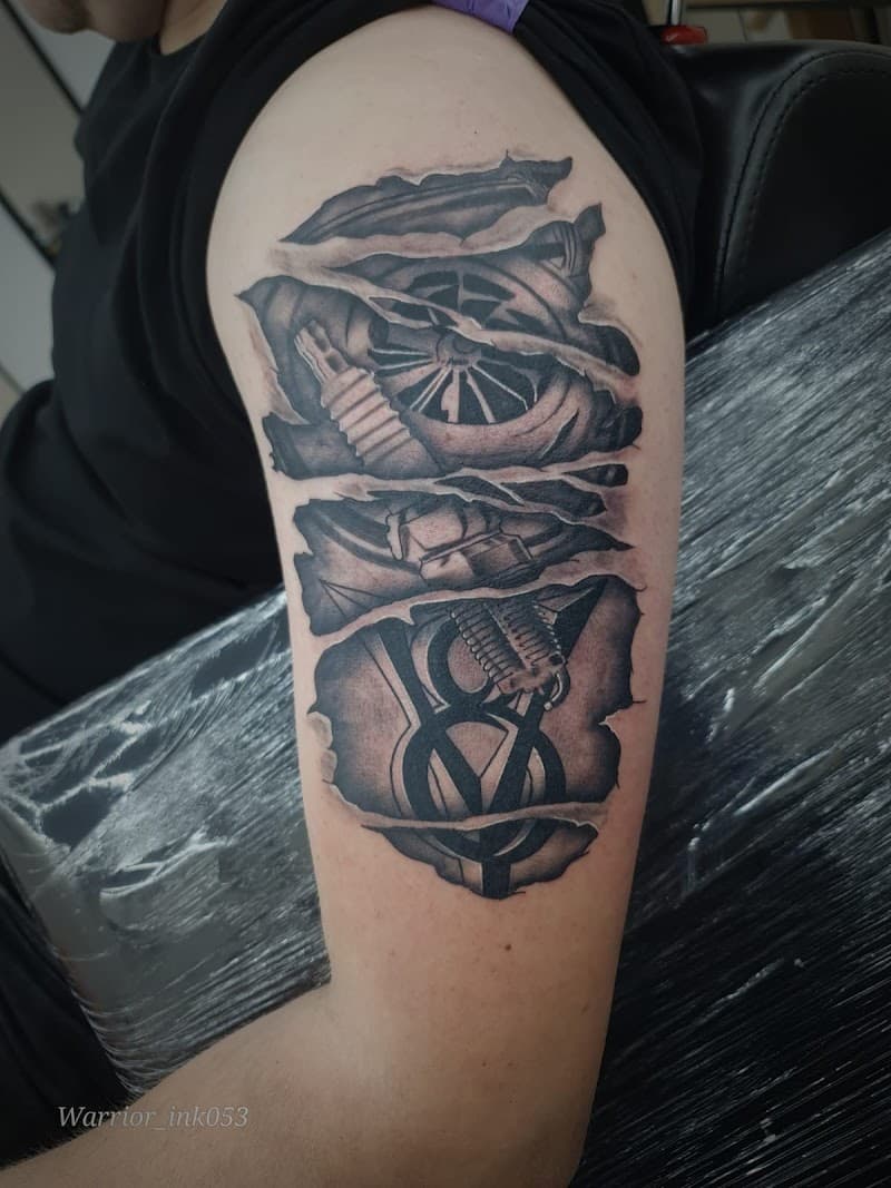 Realistische 'ripped skin' tattoo met motoronderdelen en V8 logo op bovenarm.