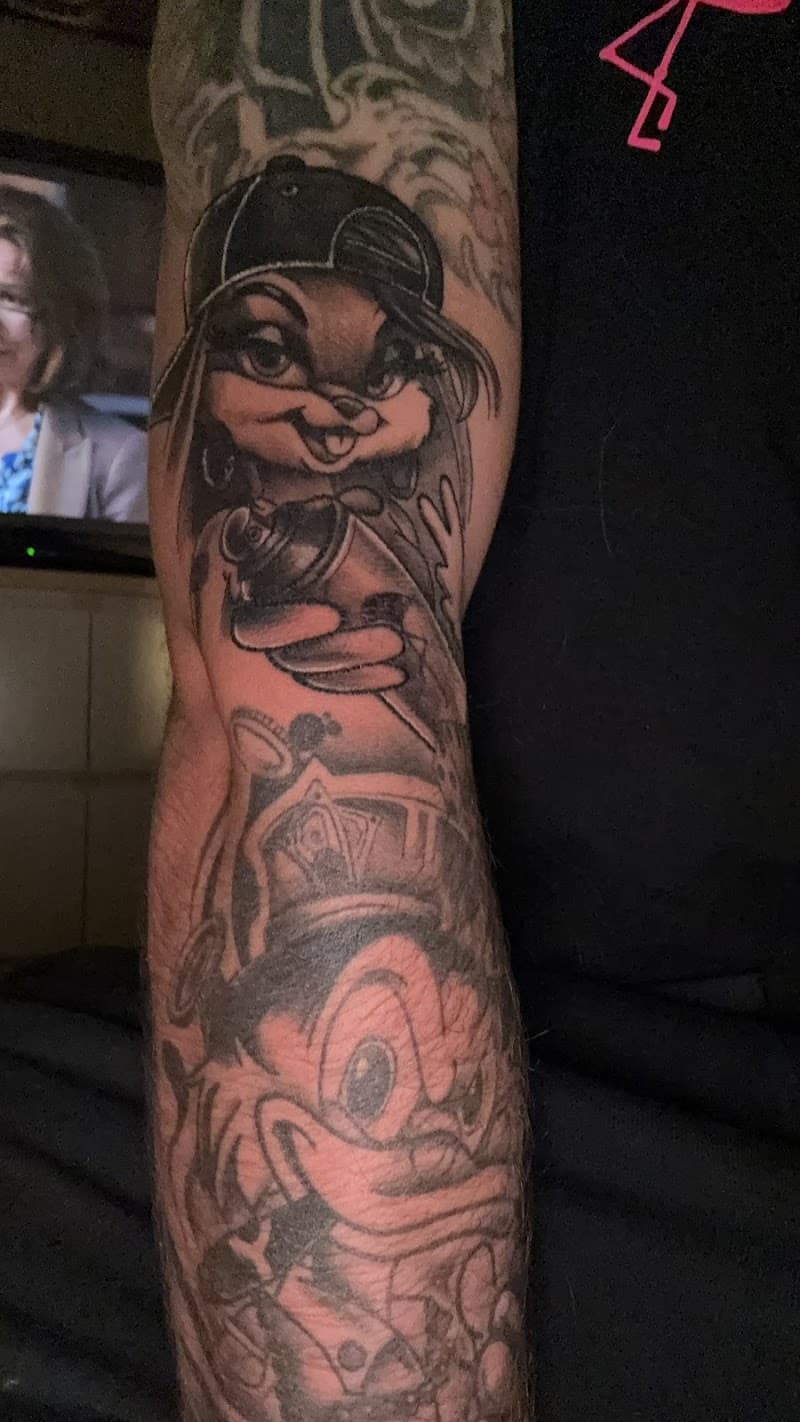 Blackwork tattoo van Lola Bunny met pet en spuitbus op de bovenarm.