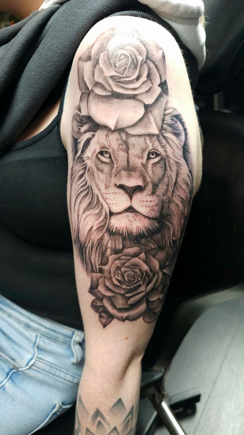 Realistische leeuwenkop met rozen op bovenarm.