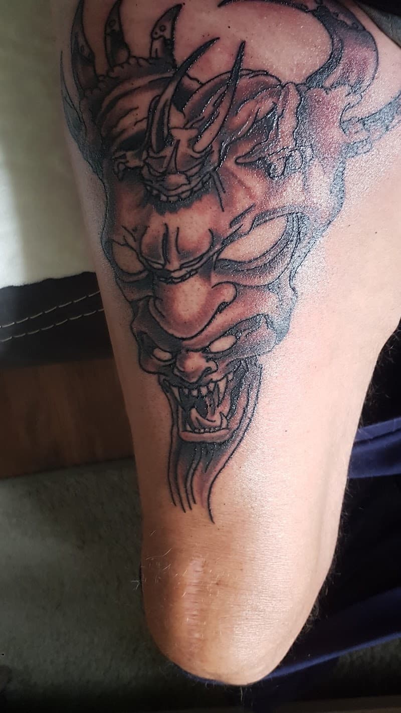 Zwart-wit Japanse Hannya masker tattoo op bovenbeen.