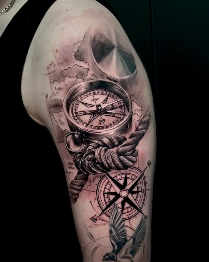 Realistische kompas, touw en landkaart tattoo op bovenarm.