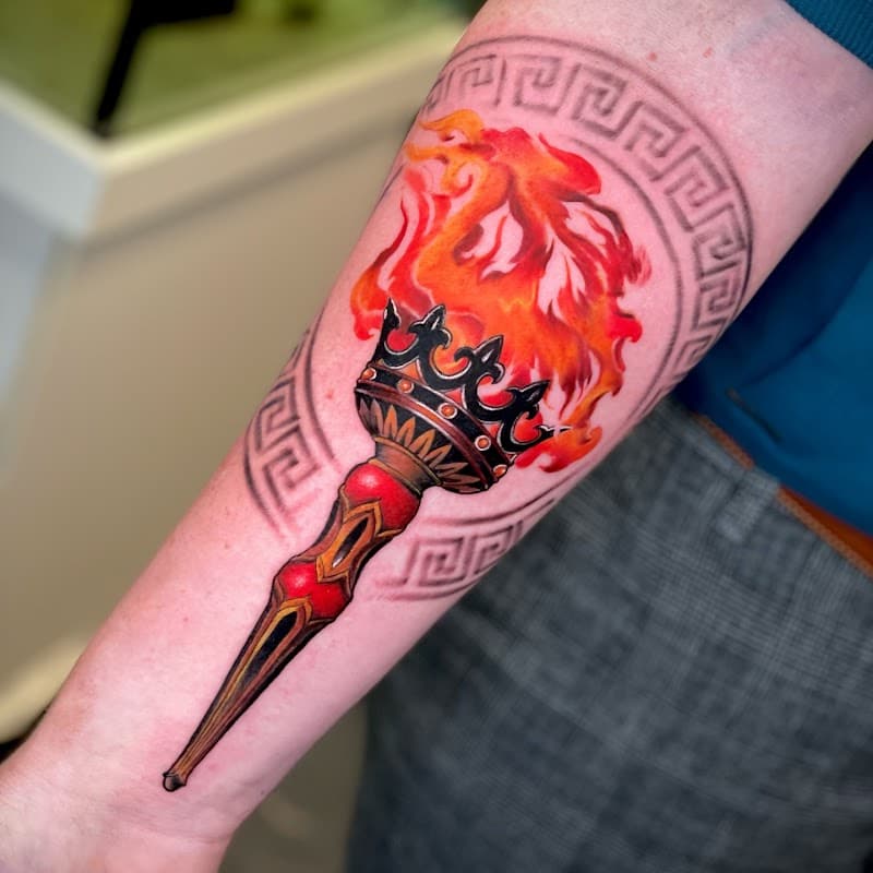 Kleurrijke fakkel met vlammen en Grieks patroon op onderarm.