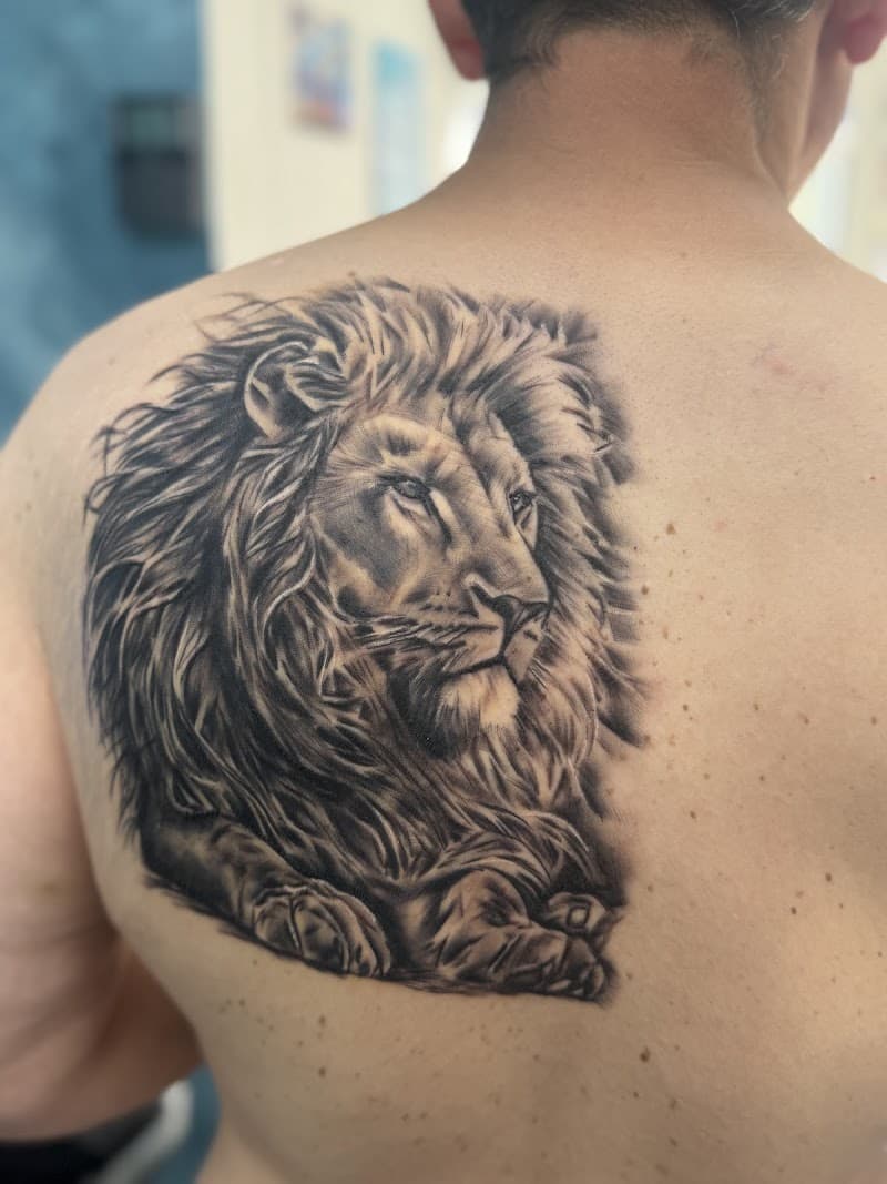 Realistische zwart-wit leeuw tattoo op de schouder/bovenrug.