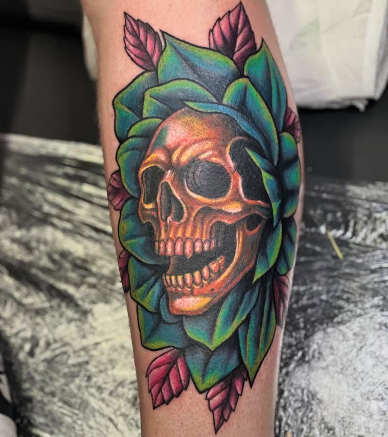 Kleurrijke schedel in groene bloem op onderbeen.