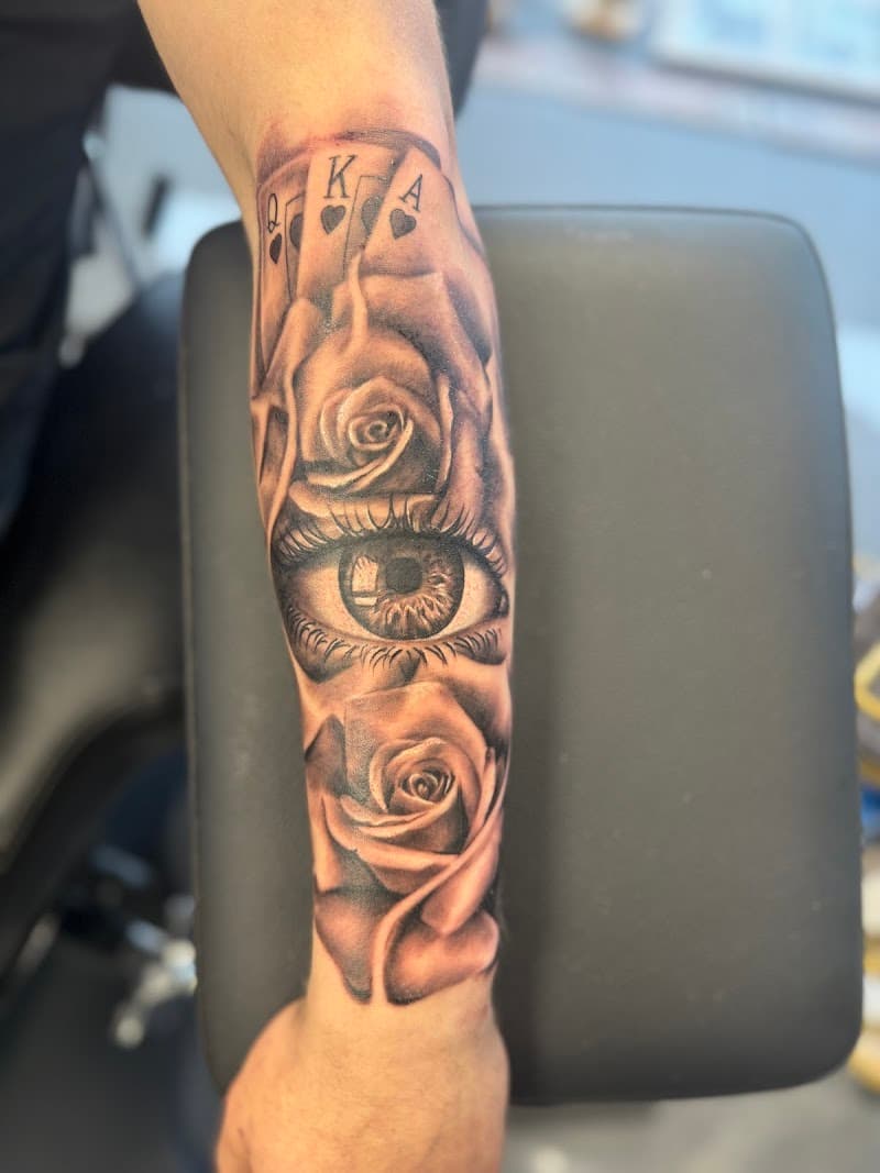 Realistisch oog met rozen en speelkaarten op onderarm.