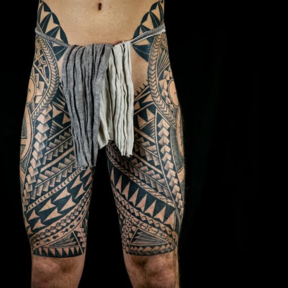 Grote Polynesische tribal tattoo op beide bovenbenen.