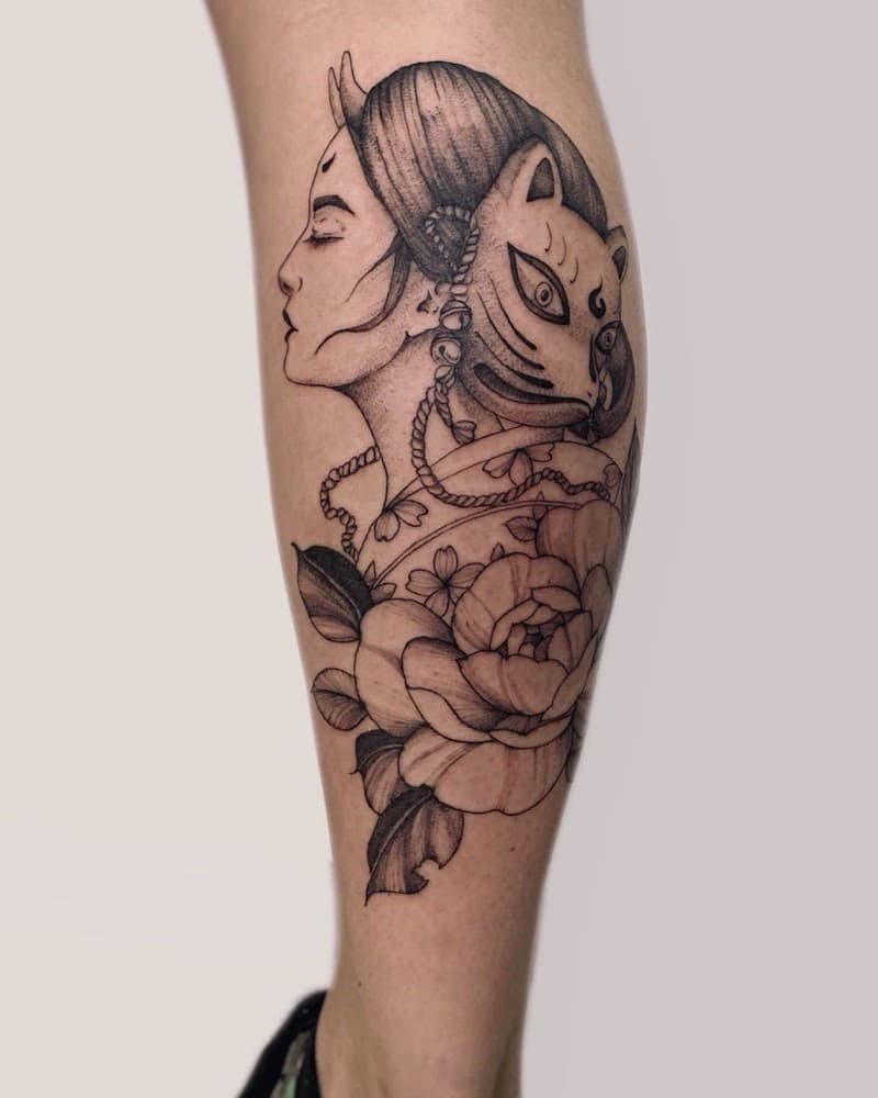 Blackwork tattoo van een vrouw met een kitsune masker en bloemen.