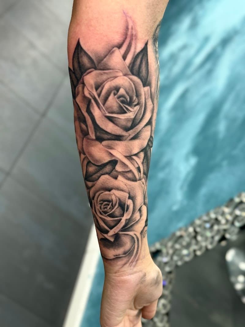 Zwart-grijze realistische tattoo van twee rozen op een onderarm.