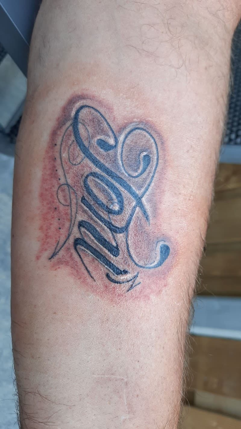 Zwart-wit lettering tattoo van de naam 'Lana' in sierlijke stijl op de onderarm.