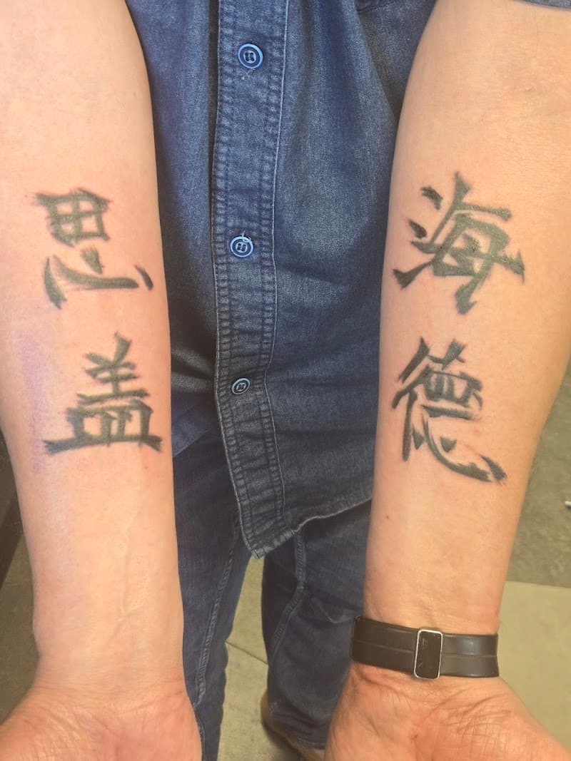 Twee Chinese karakters op elke onderarm in zwarte inkt.