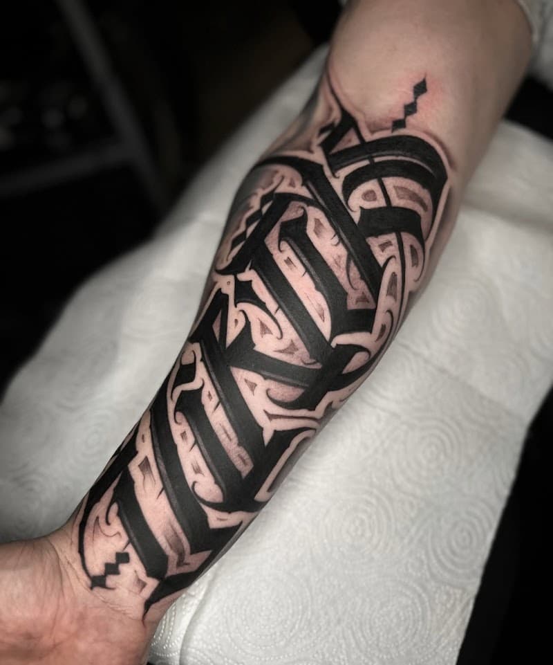 Grote blackwork lettering tattoo op de onderarm.