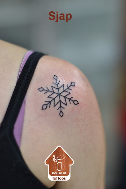 Kleine, minimalistische sneeuwvlok tattoo op de schouder.