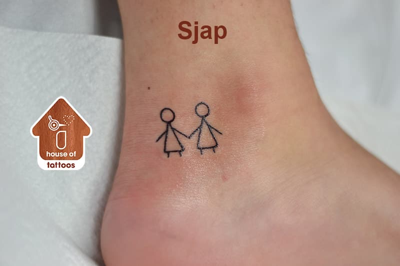 Kleine minimalistische tattoo van twee stokfiguurtjes die elkaars hand vasthouden op de enkel.