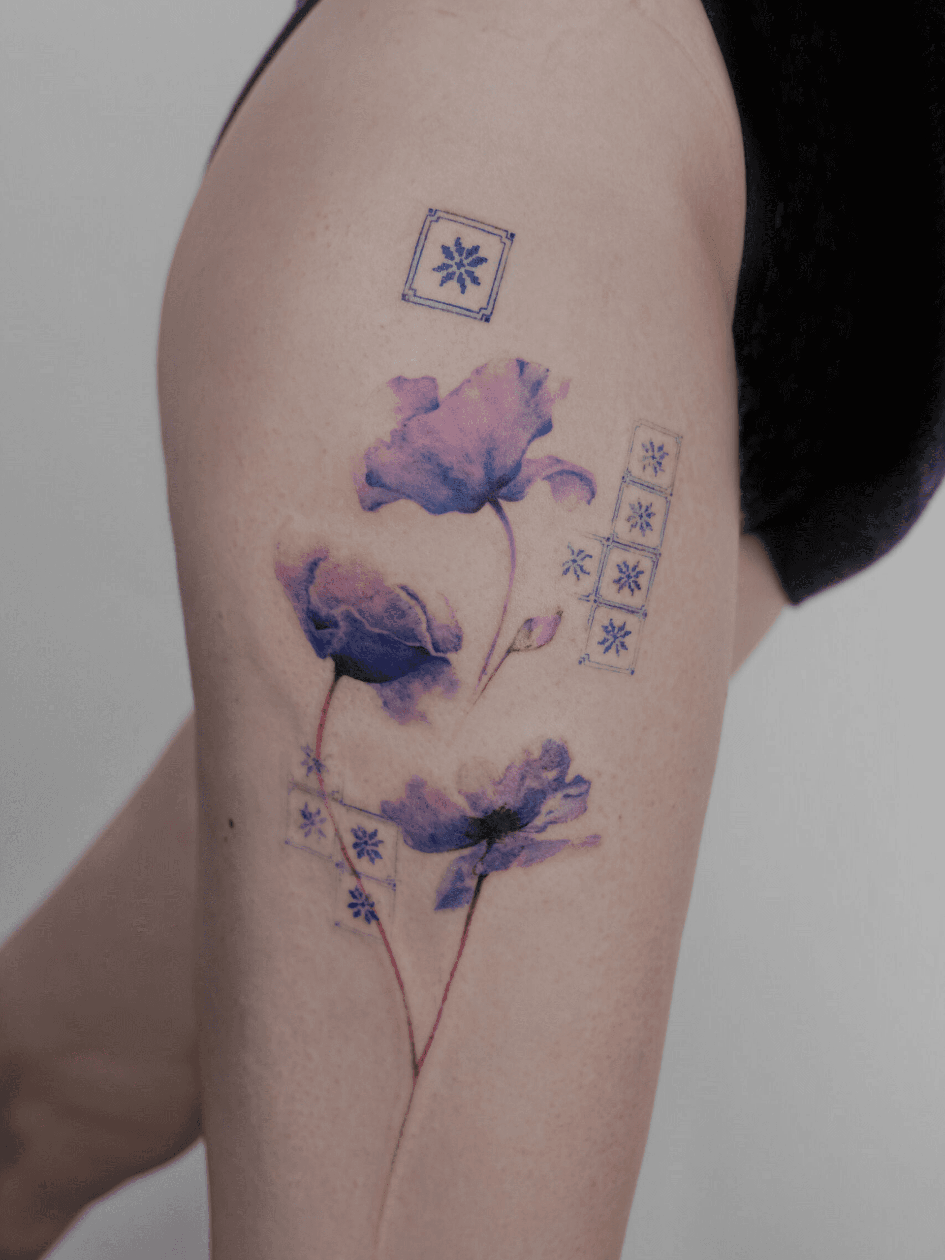 Paarse aquarel bloemen met blauwe geometrische patronen op bovenbeen.