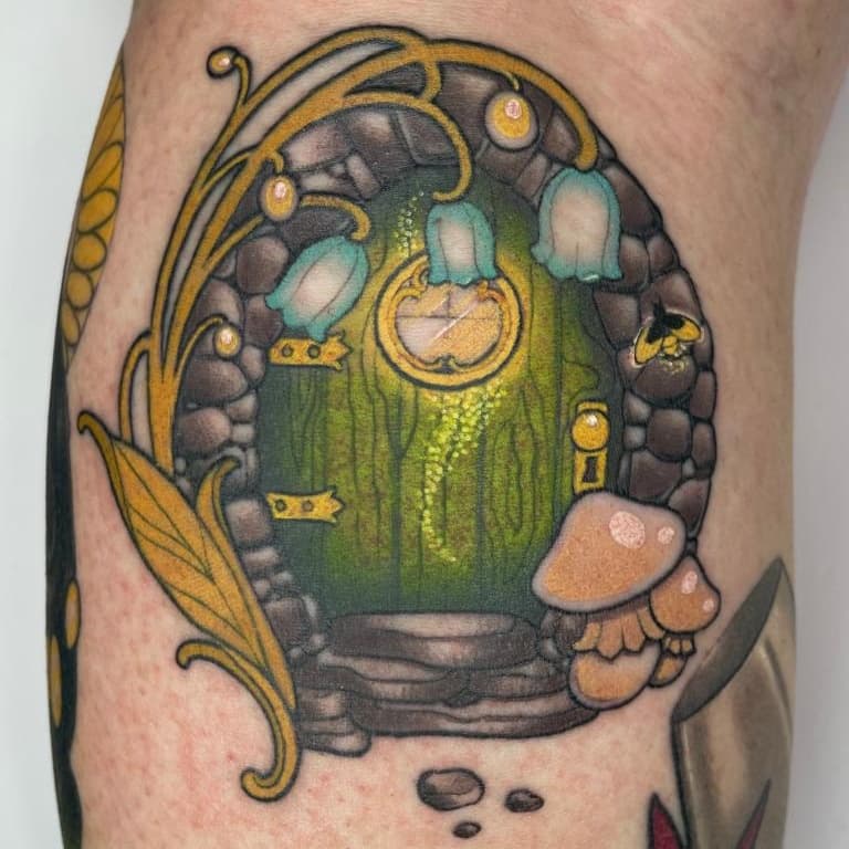 Kleurrijke illustratieve tattoo van een hobbit deur met paddenstoelen en bloemen.
