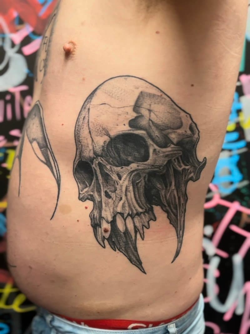 Gedetailleerde zwart-wit schedel tattoo op de ribben.