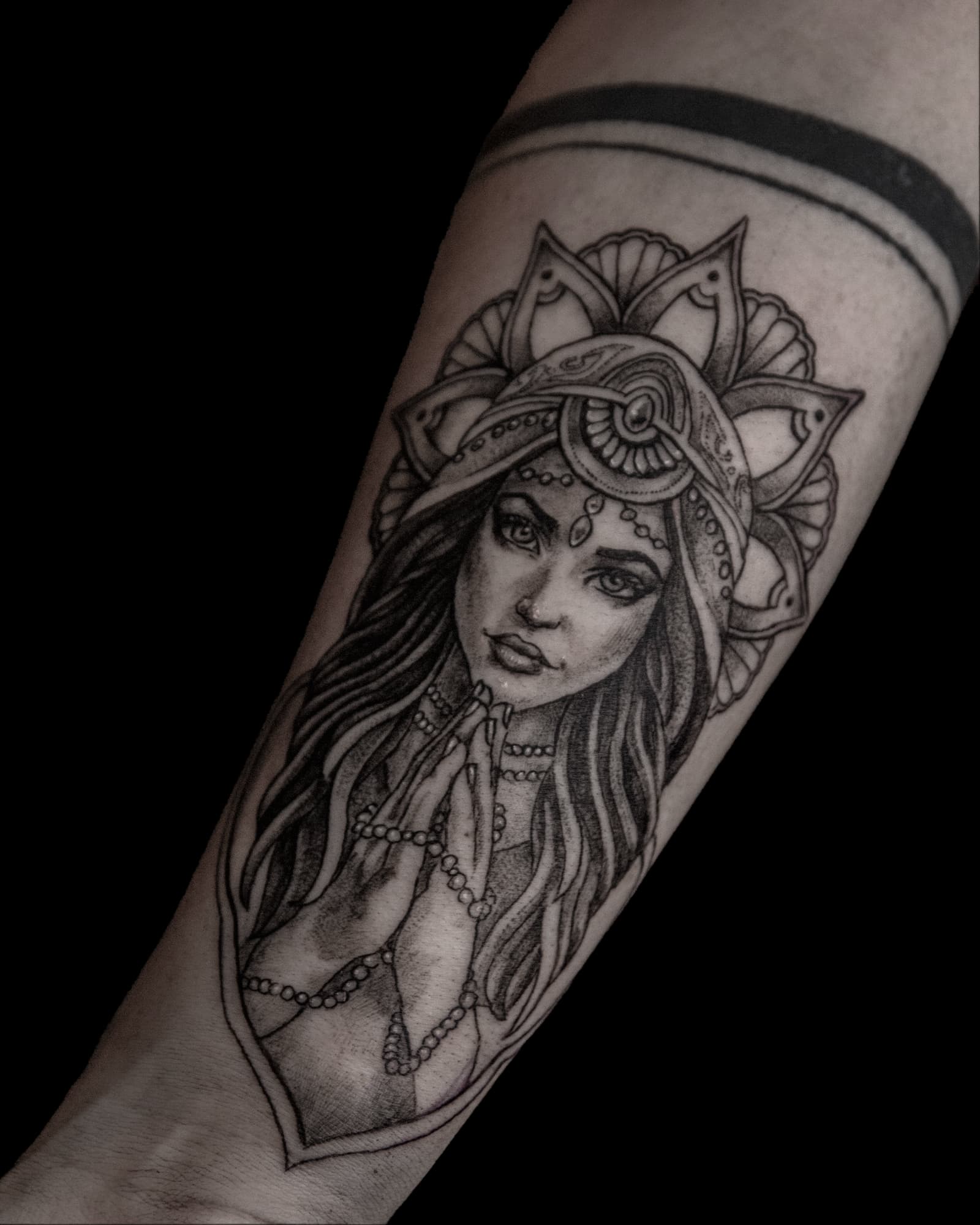 Blackwork tattoo van een biddende vrouw met een mandala hoofdtooi.