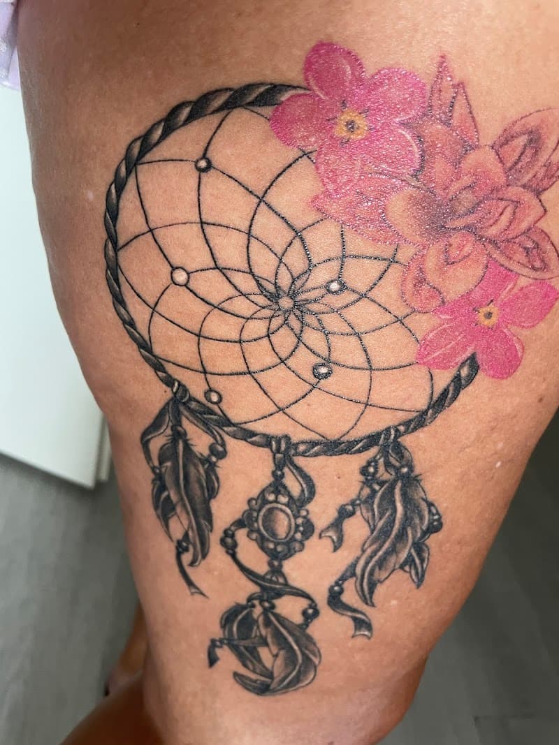 Dromenvanger met roze bloemen en veren op bovenbeen.