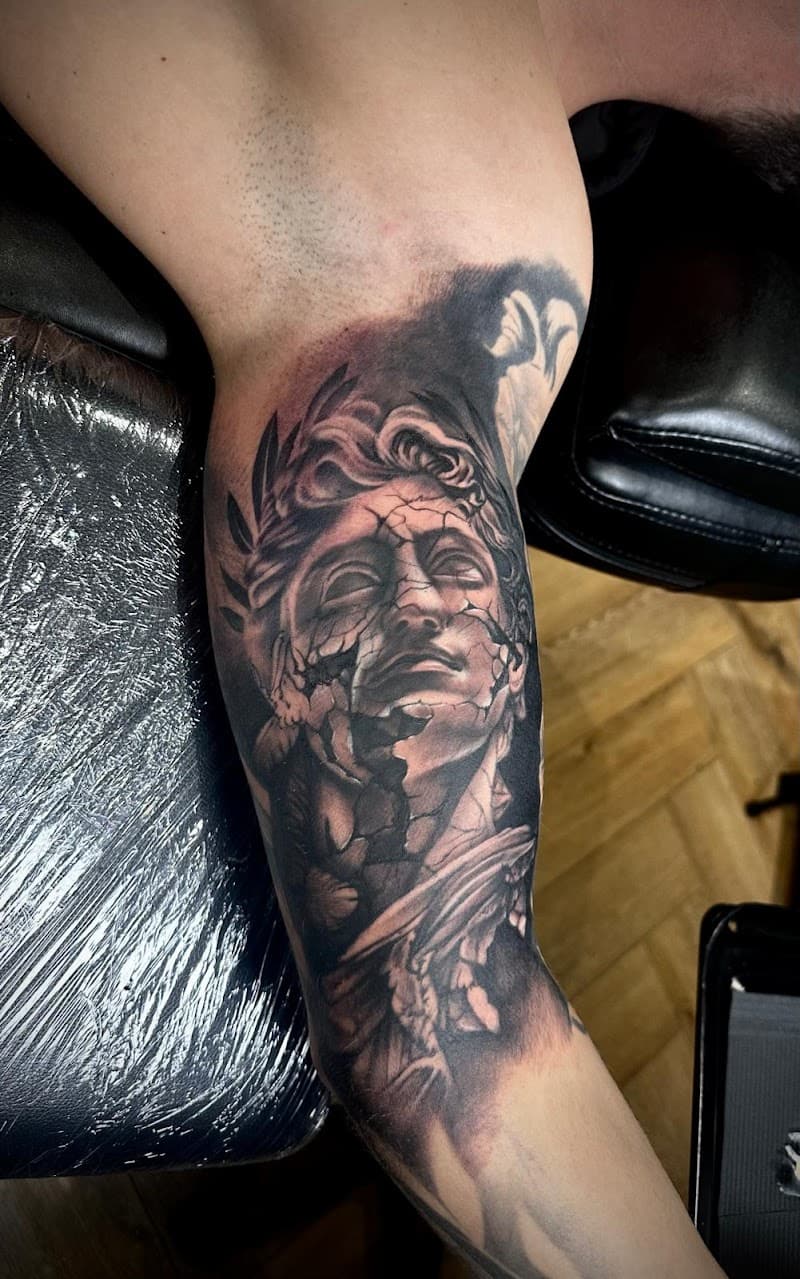 Realistische gebroken standbeeld tattoo op bovenarm.