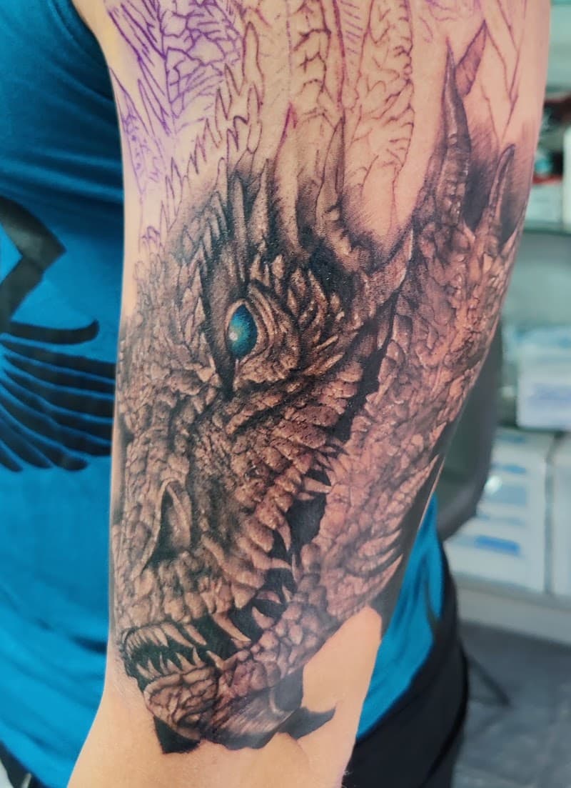 Realistische drakentattoo met blauw oog op bovenarm