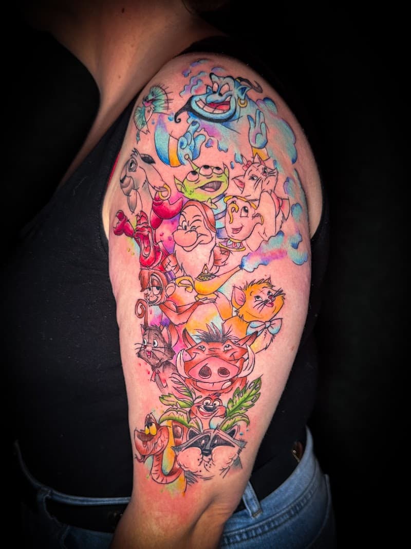 Kleurrijke Disney collage tattoo met Genie, Pumbaa, Timon en meer op bovenarm.