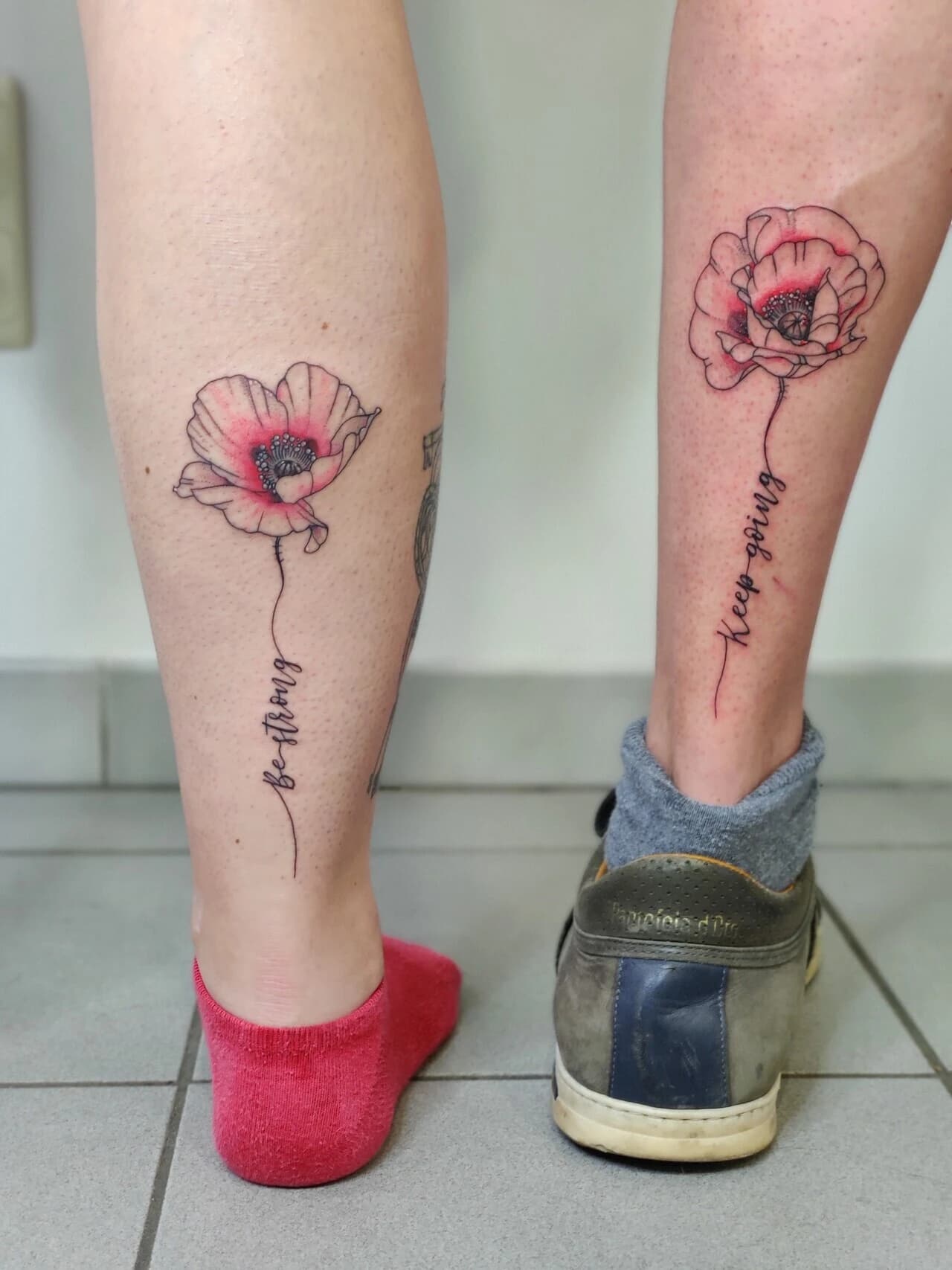 Twee fineline klaprozen met tekst 'be strong' en 'keep going' op enkels.