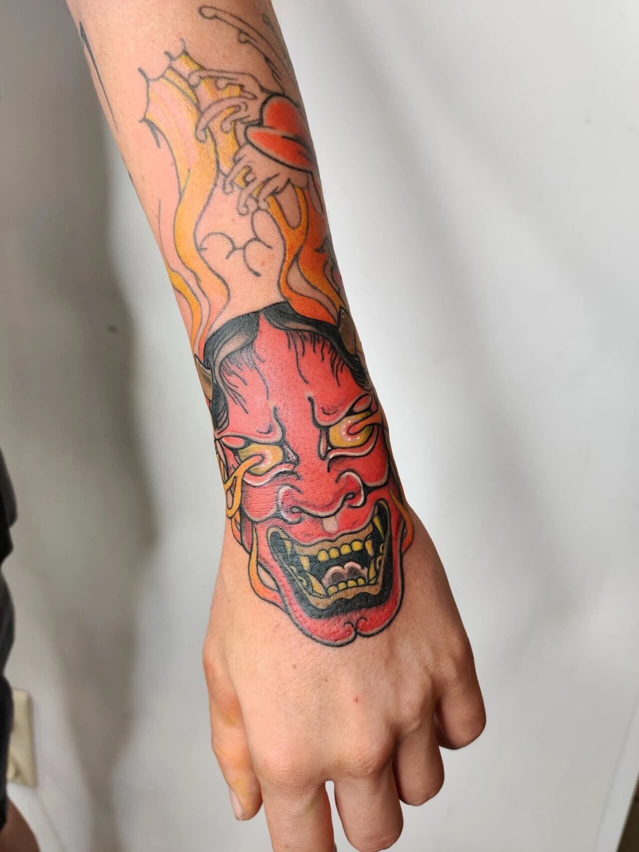Kleurrijke Japanse Hannya masker tattoo op de hand en pols.