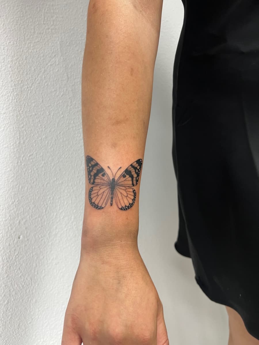 Fijne lijn vlinder tattoo op de pols.
