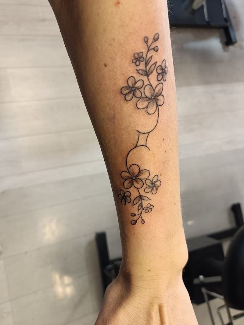 Fineline bloemen en bladeren met Tweelingen sterrenbeeld op onderarm.